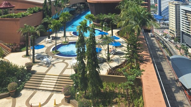 Ein Hochhotel mit Poolbereich, Palmen und einem modernen Gebäude mit einzigartigem Design.