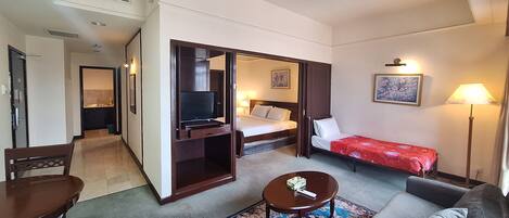 A hotel room with a bed, a TV, a desk, a sofa, and a lamp.