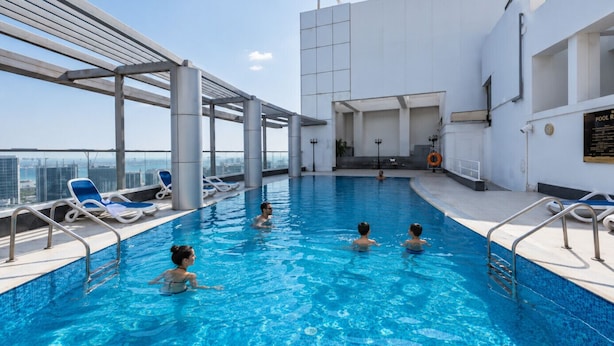 An indoor swimming pool with clear blue water, surrounded by lounge chairs and a high-rise city view. - HAVN - Studio in Downtown, Near Dubai Mall (Dubai)