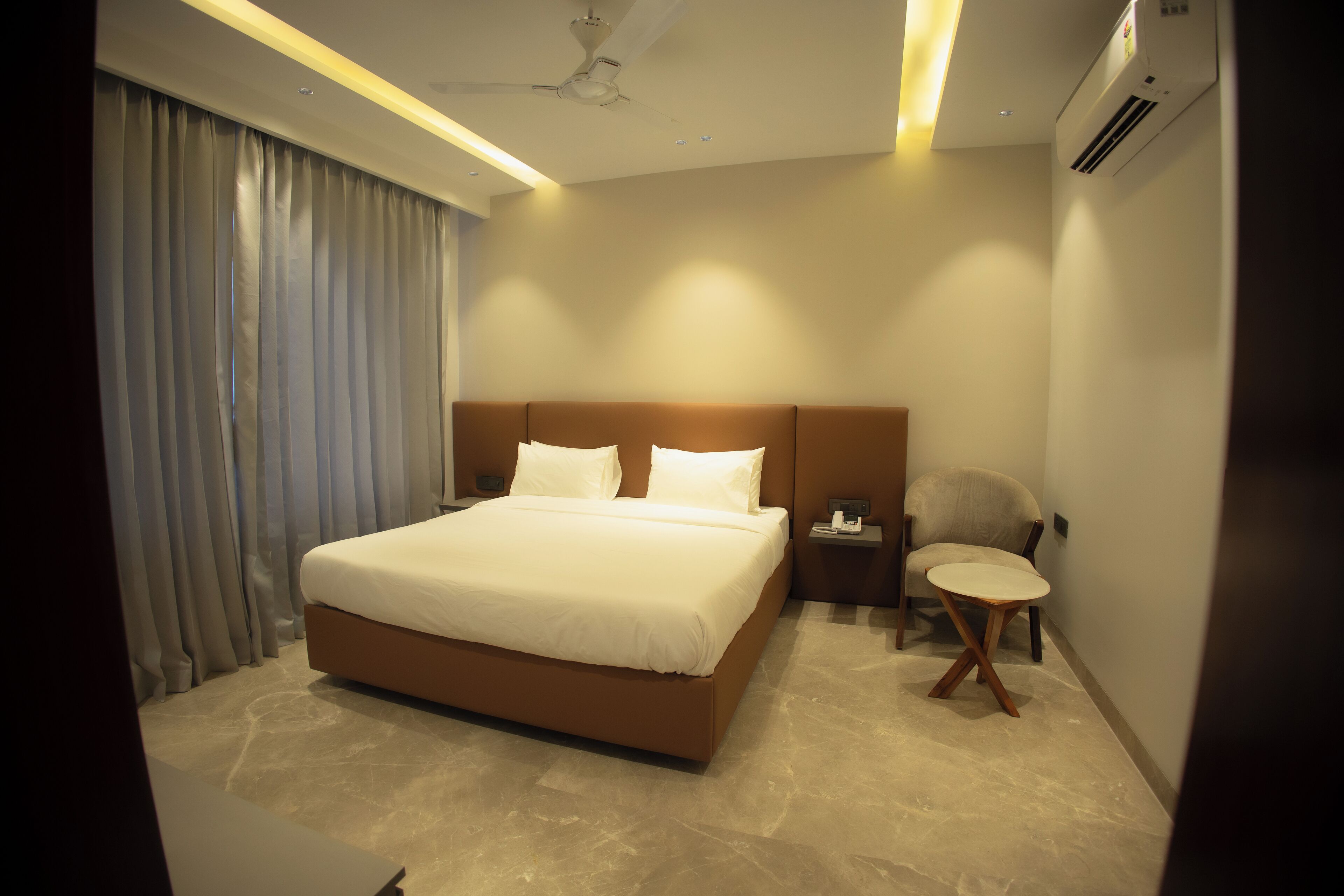 Une chambre d’hôtel moderne avec un grand lit, une table de chevet, une chaise et une petite table ronde.