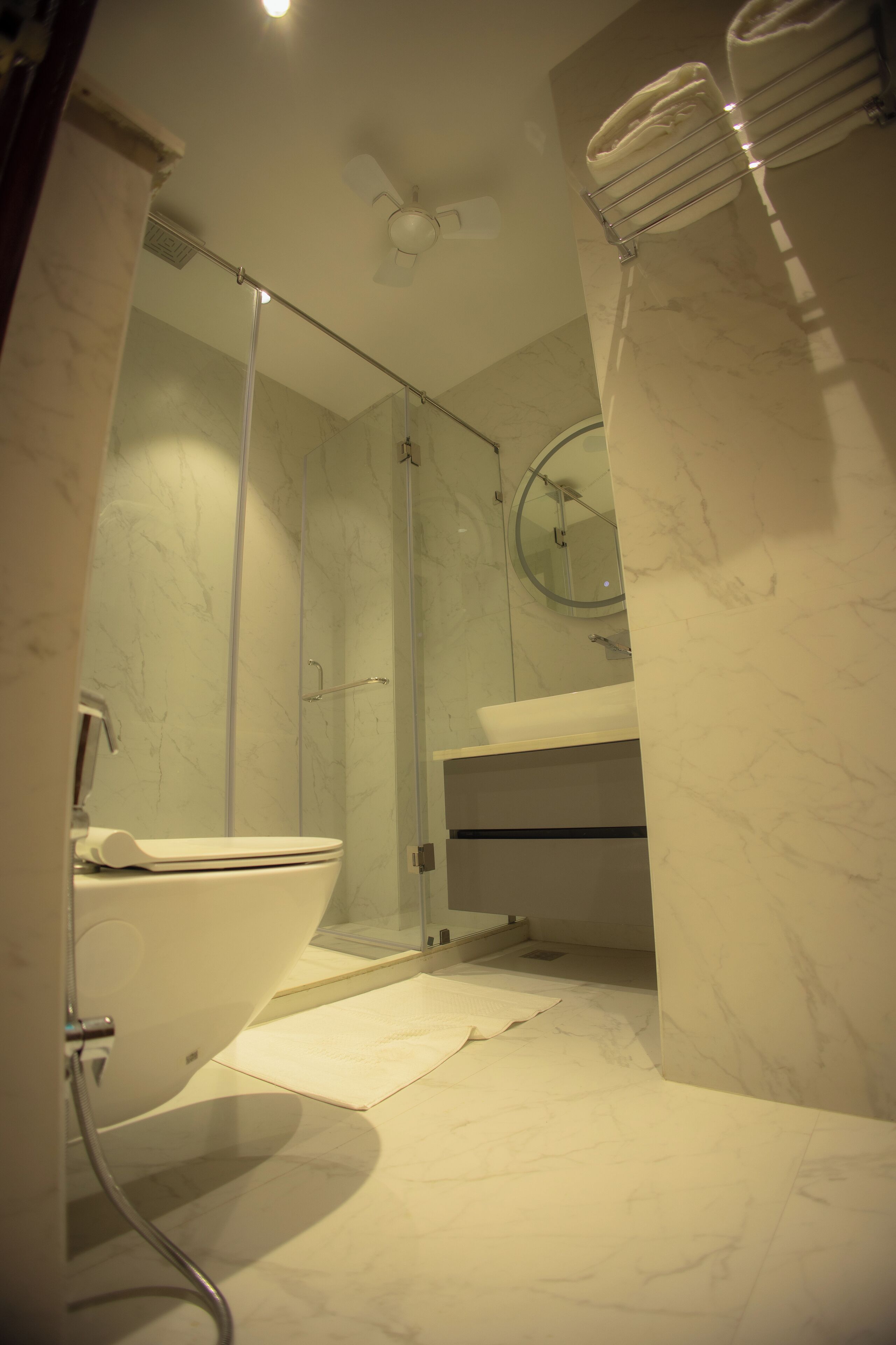 Un baño moderno con ducha de vidrio, un lavabo blanco y un inodoro.