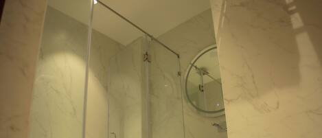 Un baño moderno con ducha de vidrio, un lavabo blanco y un inodoro.
