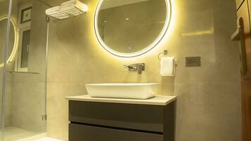 Un bagno moderno con un ampio specchio, un lavabo bianco e una cabina doccia in vetro.