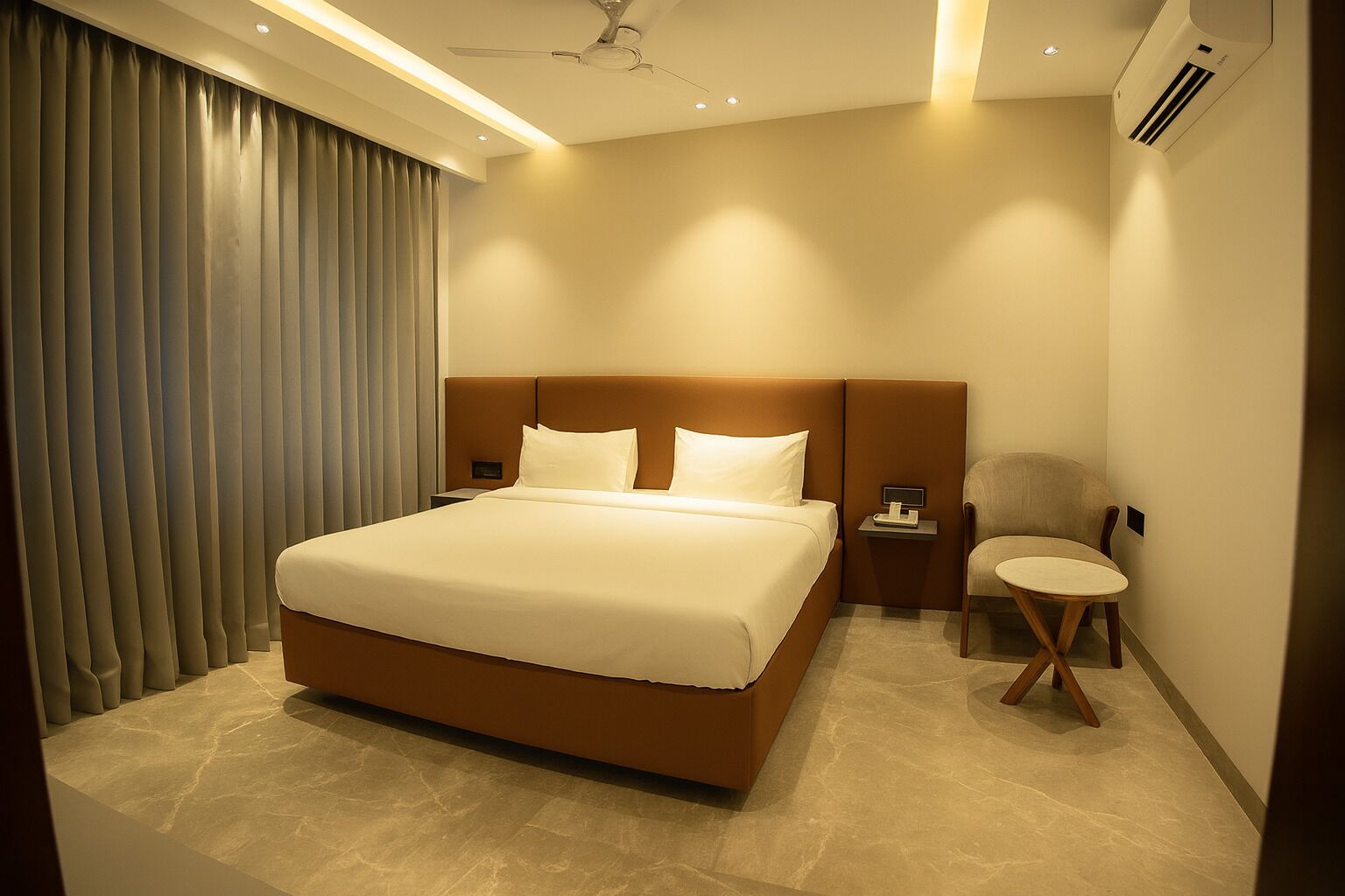 A modern hotel room with a large bed, a bedside table, a chair, and a ceiling fan.