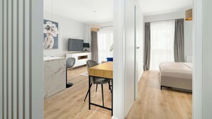 Quarto moderno com mesa de jantar de madeira, um sofá e uma televisão.