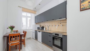 Ett modernt kök med grå skåp, en bänkskiva i trä och en matplats med bord och stolar.