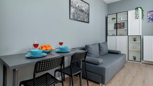 Un salon moderne avec un canapé gris, une table à manger avec des chaises et une photographie en noir et blanc encadrée accrochée au mur.