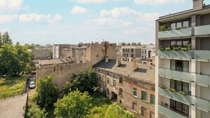 Un immeuble à plusieurs étages doté de balcons, d’une cour intérieure et entouré d’anciens bâtiments.
