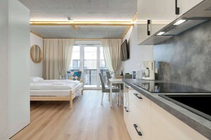 Ein modernes Hotelzimmer mit Bett, Essbereich und einer Küchenzeile.
