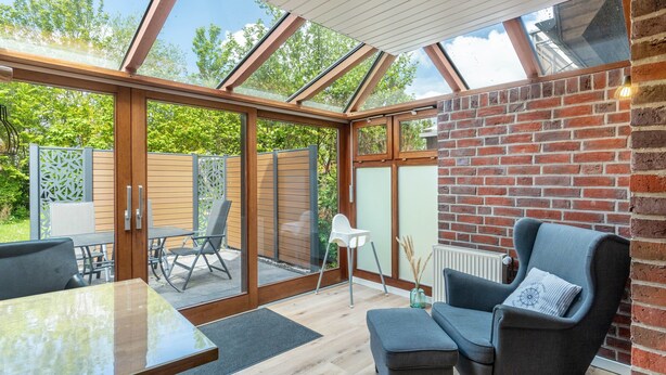 Un intérieur moderne avec un plafond en verre, un mur en briques et un espace détente comprenant une table et des chaises.