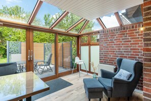 Ein modernes Interieur mit Glasdecke, Backsteinwand und einer Sitzecke mit Tisch und Stühlen.