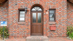 Un bâtiment en briques doté d’une porte à deux battants, de deux fenêtres et d’une boîte aux lettres.