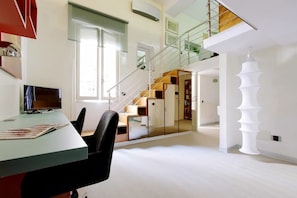 Ein modernes Interieur mit einer Treppe, einem Schreibtisch mit Computer und einem großen Spiegel.