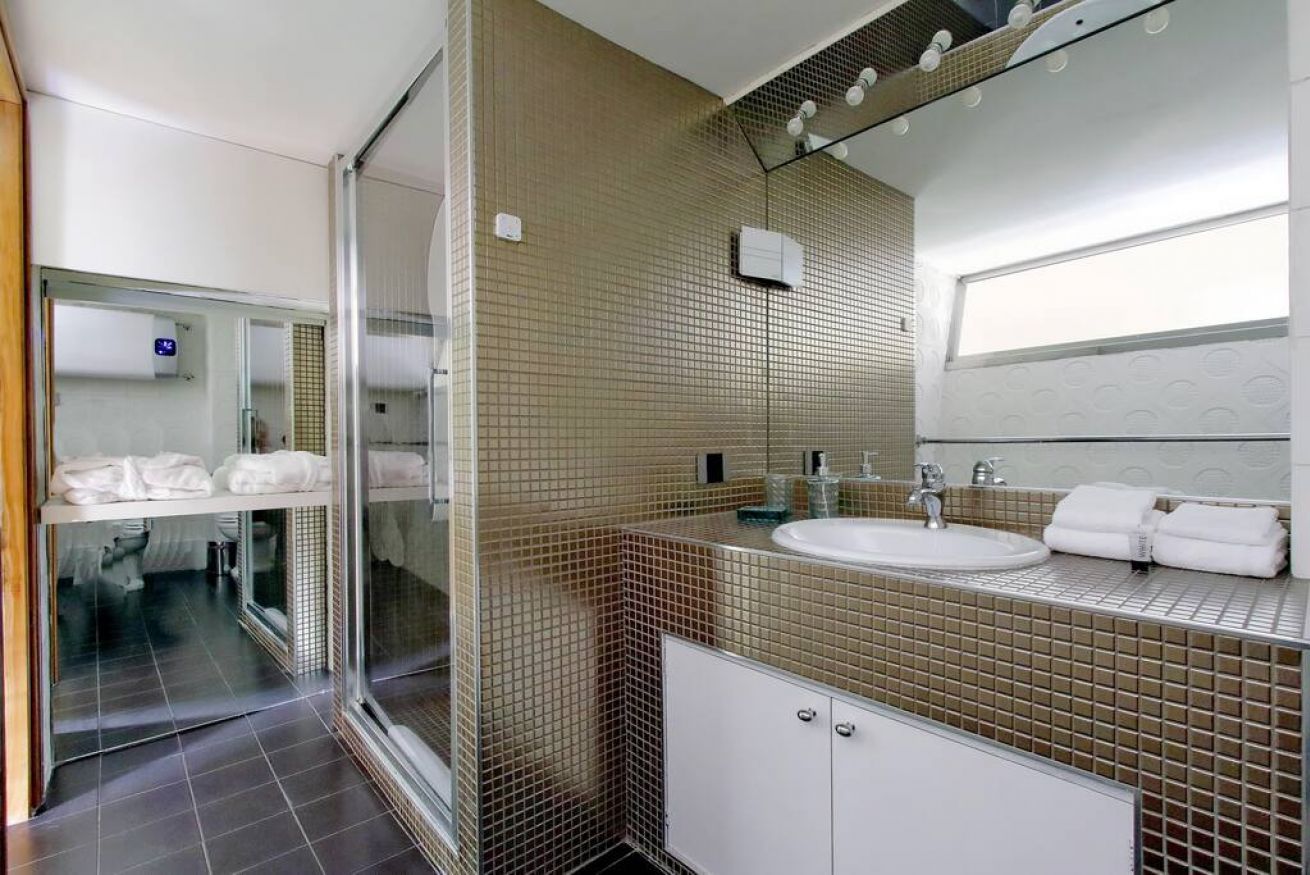 A modern bathroom with a glass shower enclosure, a white sink, and a tiled backsplash.