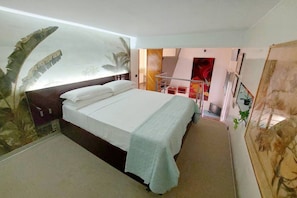 A modern hotel room with a large bed, a small desk, and a balcony with a red railing. - MARGUTTA LOFT FOR SMART WORKER (Roma)