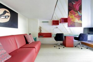 A modern living room with a red sofa, a desk with two chairs, and artwork on the walls. - MARGUTTA LOFT FOR SMART WORKER (Roma)
