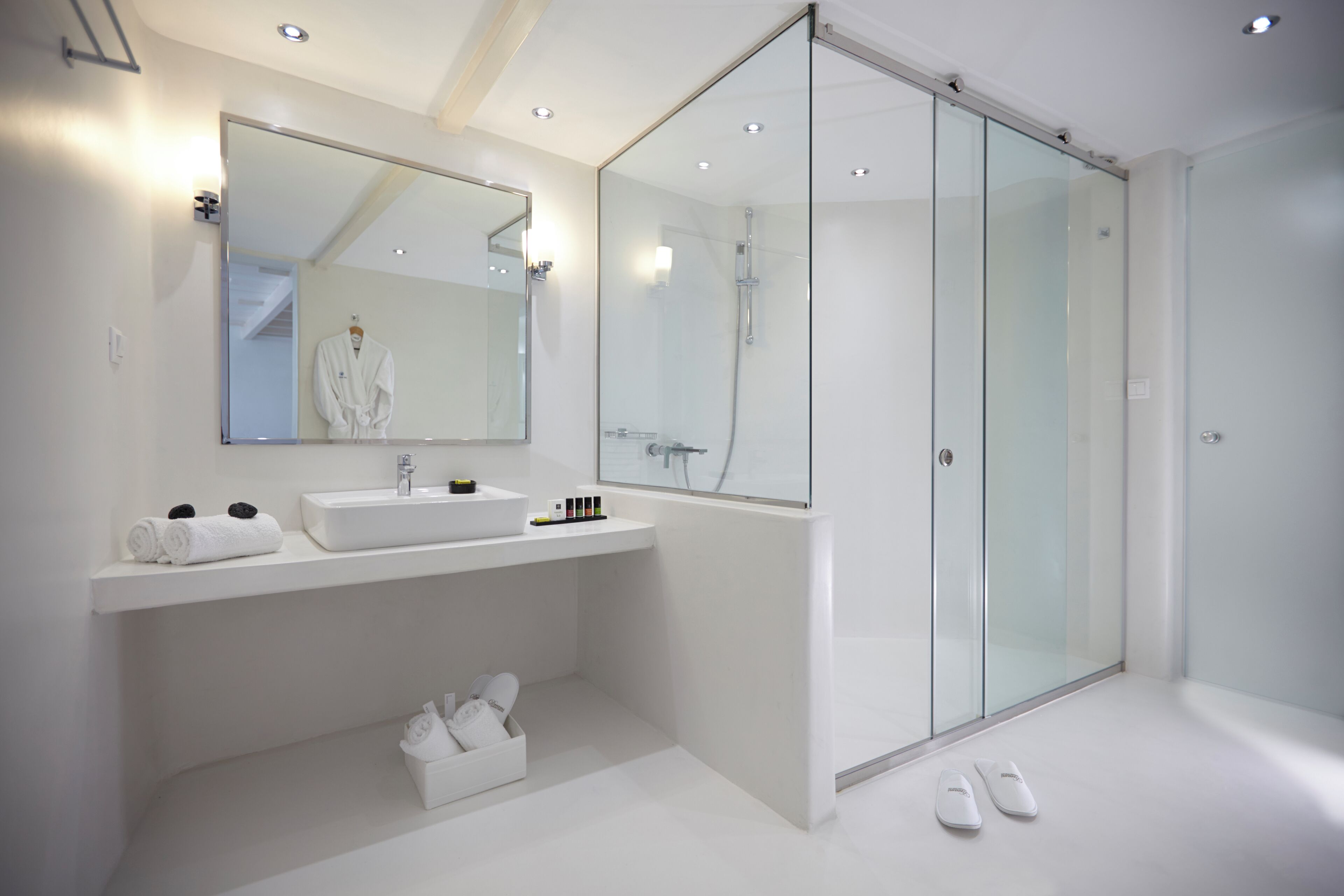 Un baño moderno con un espejo grande, un lavabo y una ducha con mampara de vidrio.