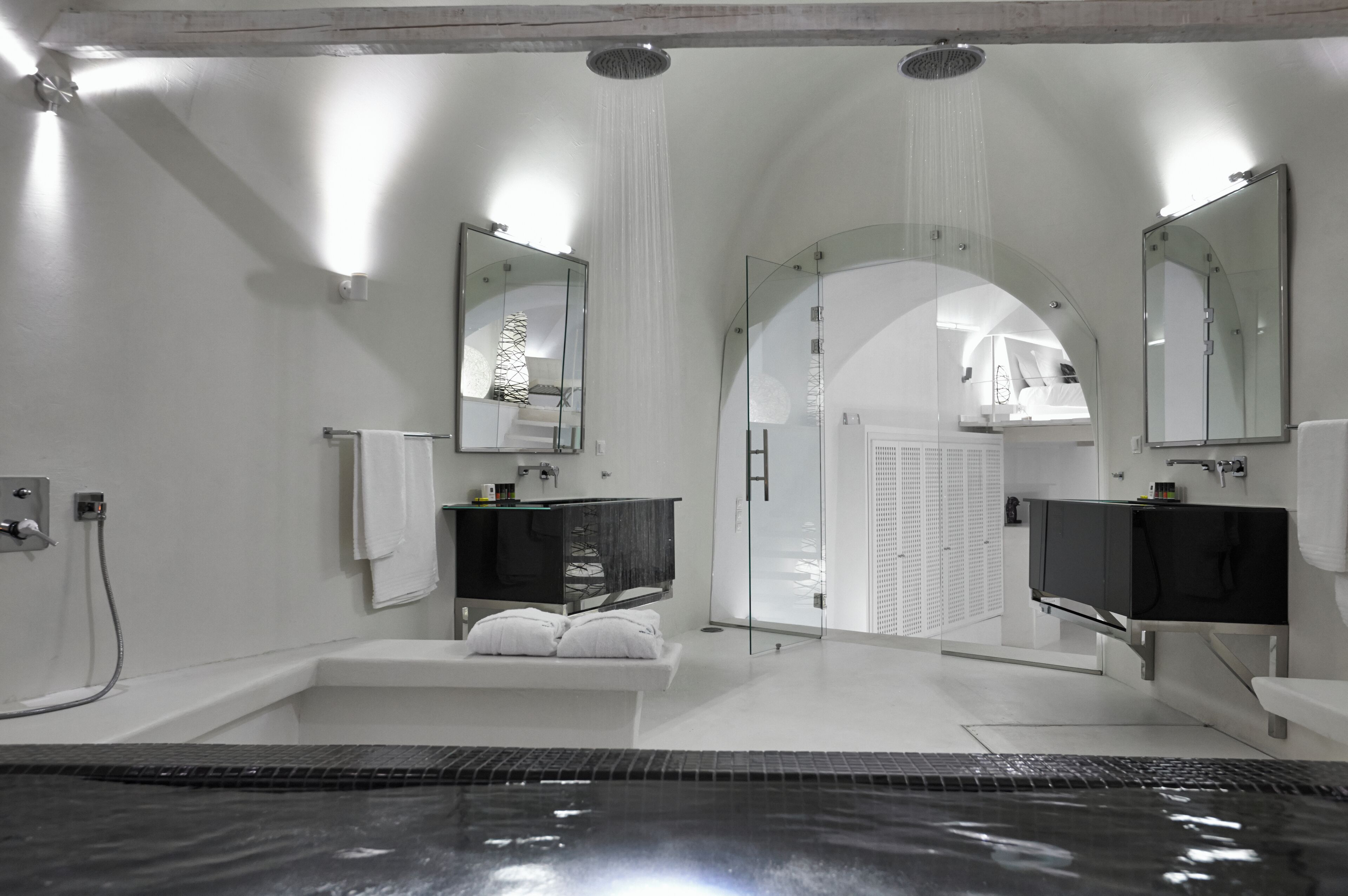 Un baño moderno con bañera, dos lavamanos y zona de ducha con mampara de cristal.
