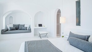 A modern, minimalist bedroom with a large bed, a sofa bed, and a small table. - Cloud 9 (Santorini)