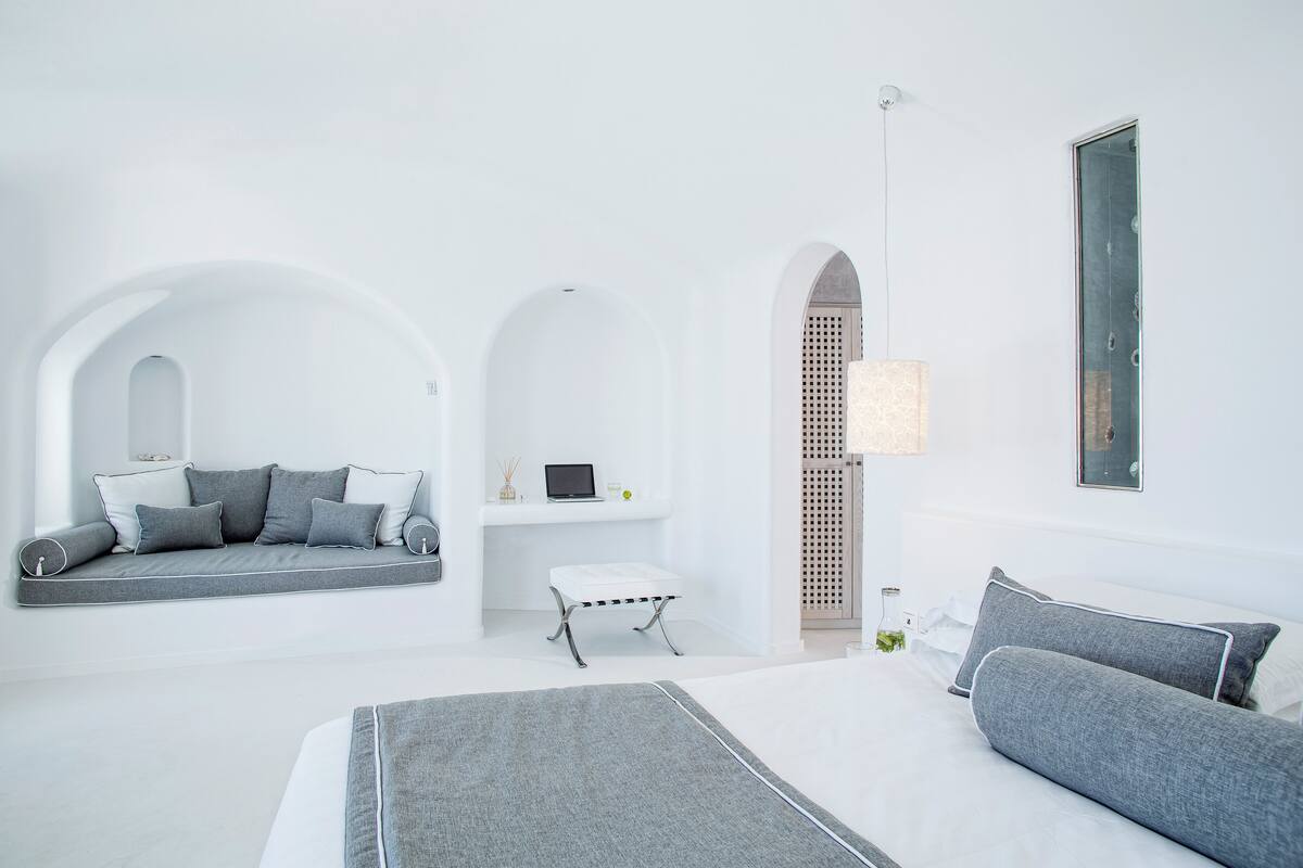 A modern, minimalist bedroom with a large bed, a sofa bed, and a small table.