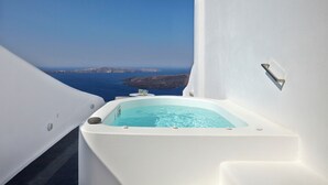 A white infinity pool with clear blue water, a stone on the edge, and a view of the sea and islands in the background. - Cloud 9 (Santorini)