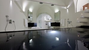 A modern bathroom with a large mirror, a bathtub, and a shower area. - Cloud 9 (Santorini)
