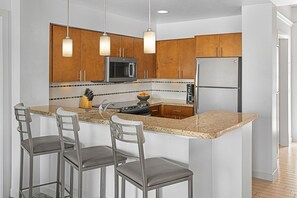 Una cocina moderna con armarios de madera, electrodomésticos de acero inoxidable y encimera de granito.