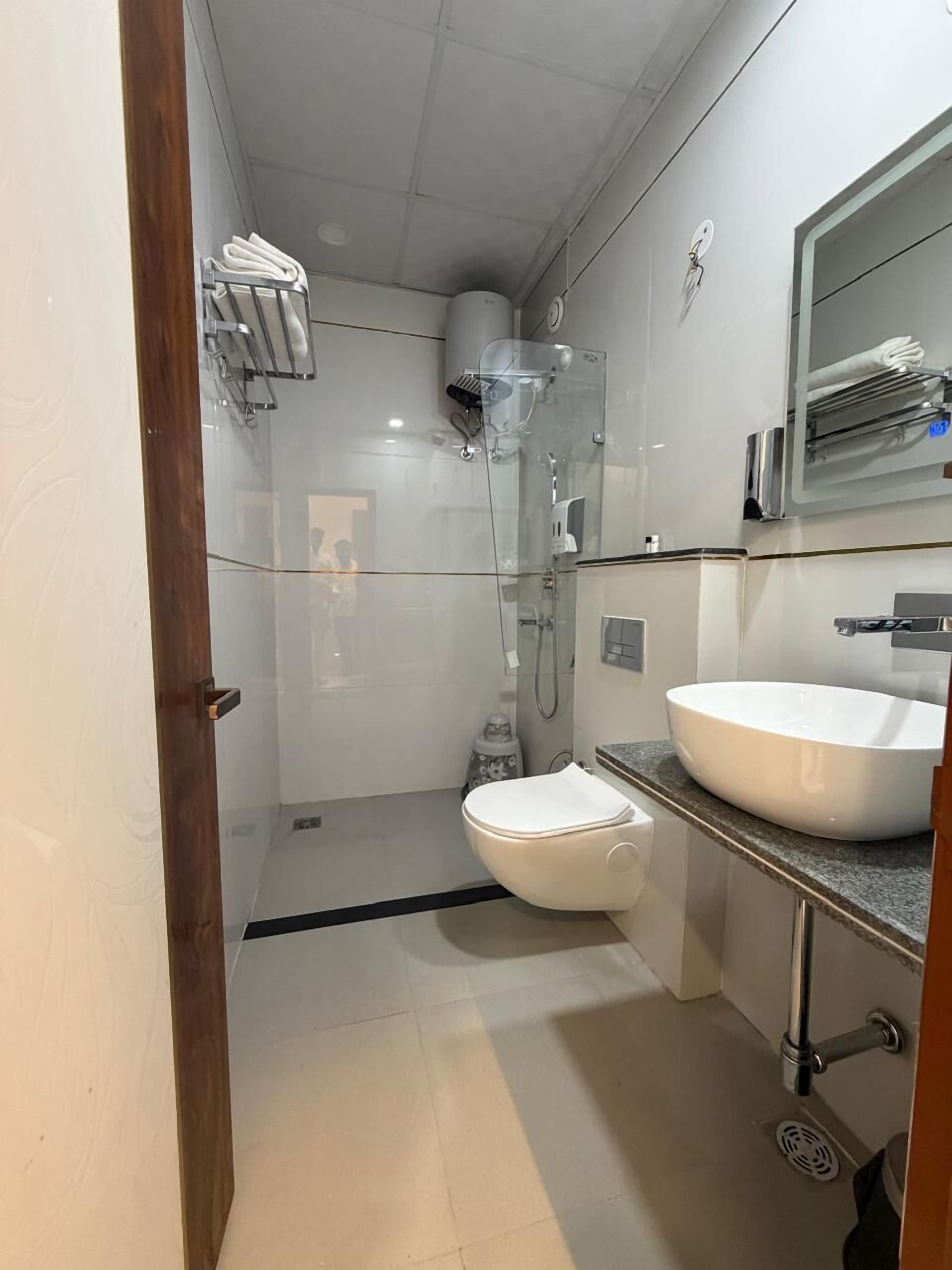 A modern bathroom with a glass-enclosed shower, a white toilet, and a large sink.
