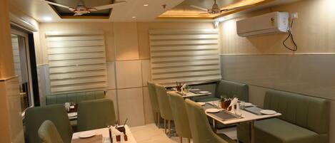Un restaurante con cabinas y mesas, ventiladores de techo y un diseño moderno.