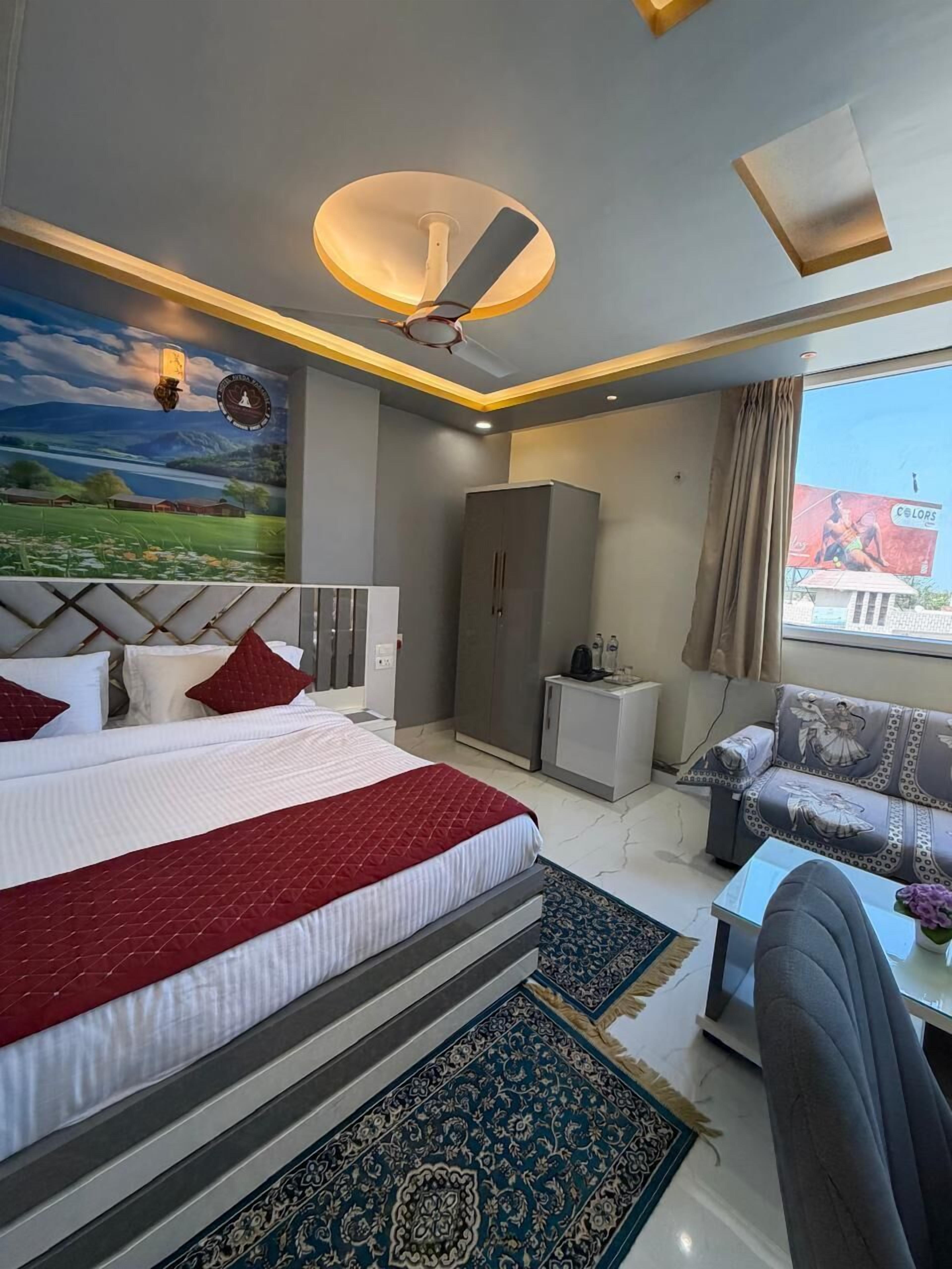 A modern hotel room with a large bed, a sofa, a desk, and a view of the outdoors.
