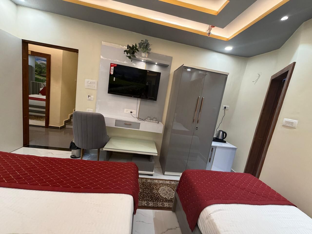Een hotelkamer met twee bedden, een bureau, een televisie en een kledingkast.