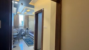 A hotel corridor with a wooden door frame, a sign indicating room number 302, and a glimpse of a bedroom with a bed, curtains, and a nightstand. - Hotel Aveda Paradise (Varanasi)