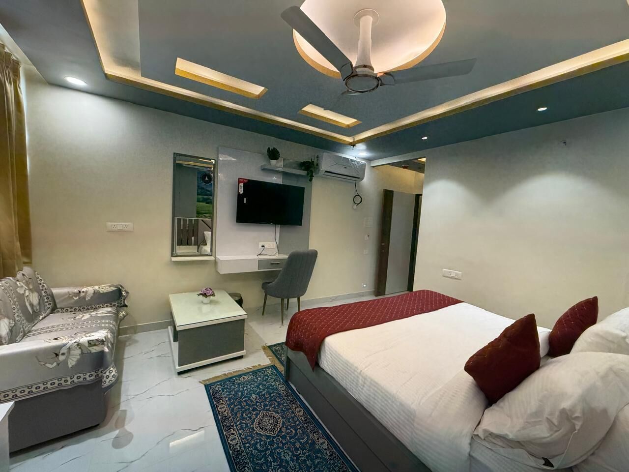 Ein modernes Schlafzimmer mit Bett, Schreibtisch, Stuhl, Sofa und Fernseher.
