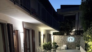 A covered outdoor area with a seating arrangement, a stone wall, and a balcony. - Sweet & Home 1 LOFT on two levels near bergamo (Azzano San Paolo)