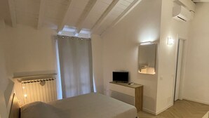 A bedroom with a wooden bed, a nightstand, a TV, and a mirror. - Sweet & Home 1 LOFT on two levels near bergamo (Azzano San Paolo)