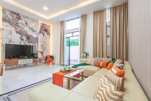 Ein modernes Wohnzimmer mit Flachbildfernseher, einer Sofagarnitur, einem Couchtisch und einer Marmorwand.