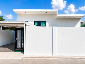Ein modernes, zweistöckiges Haus mit Flachdach, überdachter Auffahrt und geschlossenem Eingangstor.