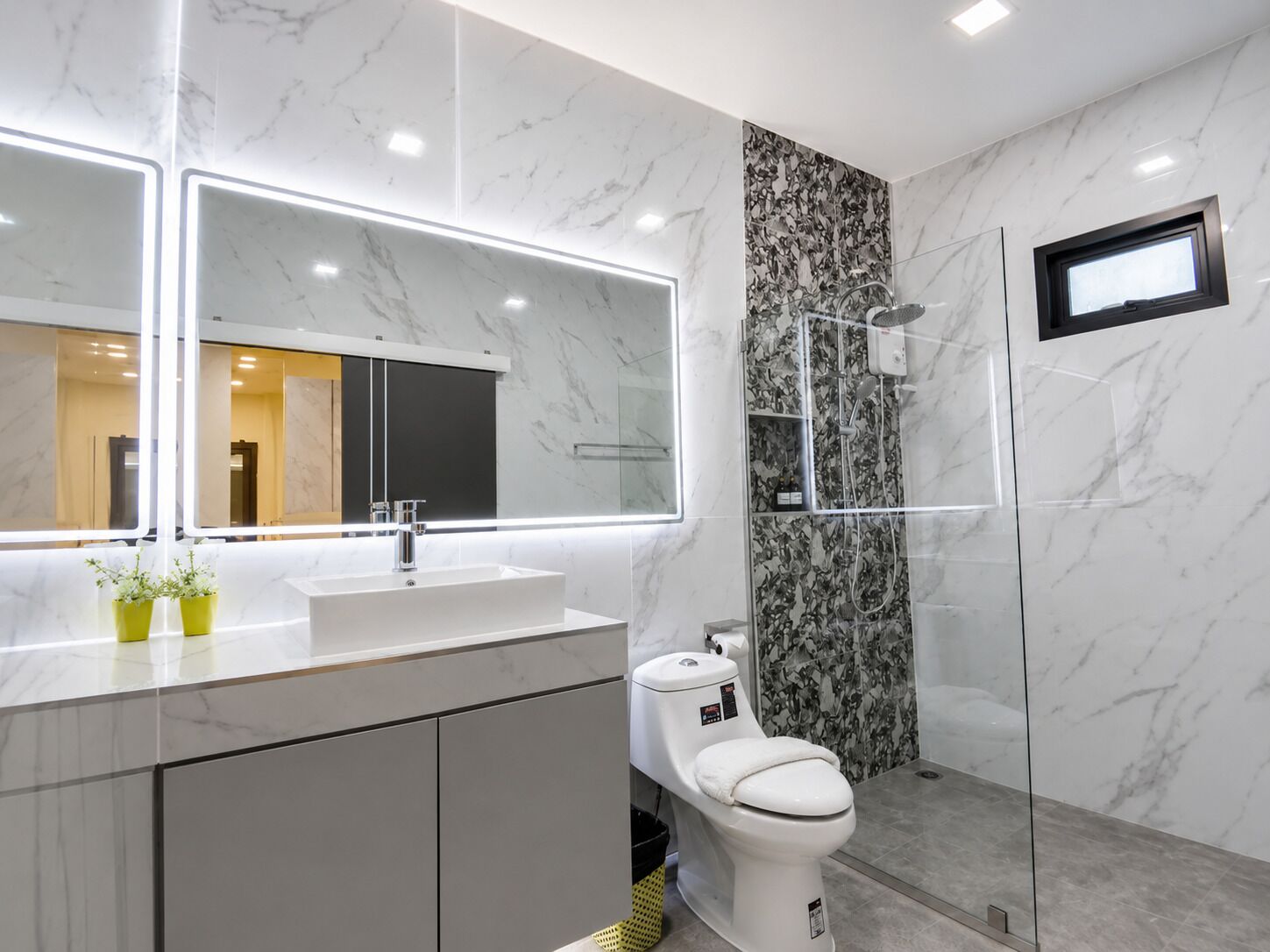 A modern bathroom with a large mirror, a sink, a toilet, and a shower area.
