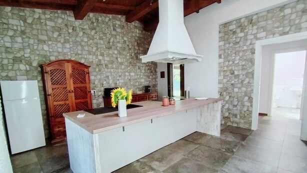 A kitchen with a stone wall, a wooden cabinet, a white countertop, and a white sink. - Sunflowers abode Your rustic home in the center of all Tuscan destinations! (Toscana)