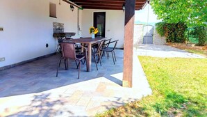 An outdoor patio with a wooden table and chairs, a stone wall, and a door. - Sunflowers abode Your rustic home in the center of all Tuscan destinations! (Toscana)