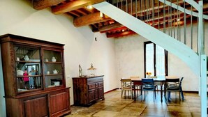 A spacious room with a wooden cabinet, a dining table with chairs, and a staircase with a white railing. - Sunflowers abode Your rustic home in the center of all Tuscan destinations! (Toscana)