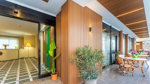 A modern hotel lobby with a checkered floor, wooden paneling, potted plants, and a seating area with wicker chairs and tables. - Stylish Residence House in Alghero (Alghero)