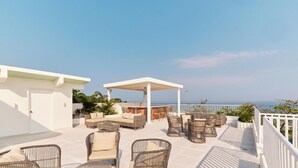 A rooftop terrace with outdoor furniture, a covered seating area, and a view of the sea.