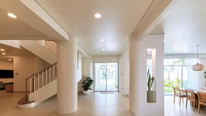 A spacious interior with a staircase, a dining area, and a large window providing a view of the outdoors.