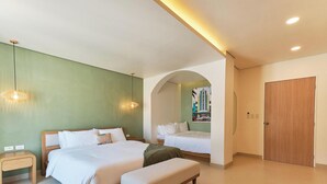A hotel room with two beds, a small bedside table, a wooden door, and a wall with a cityscape mural.