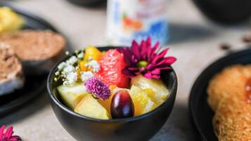 A bowl of fruit salad with various fruits and flowers.