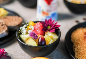 A bowl of fruit salad with various fruits and flowers.