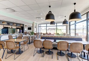 A modern restaurant with high tables, chairs, and pendant lighting. - B&B Hotel Moulins Avermes (Avermes)