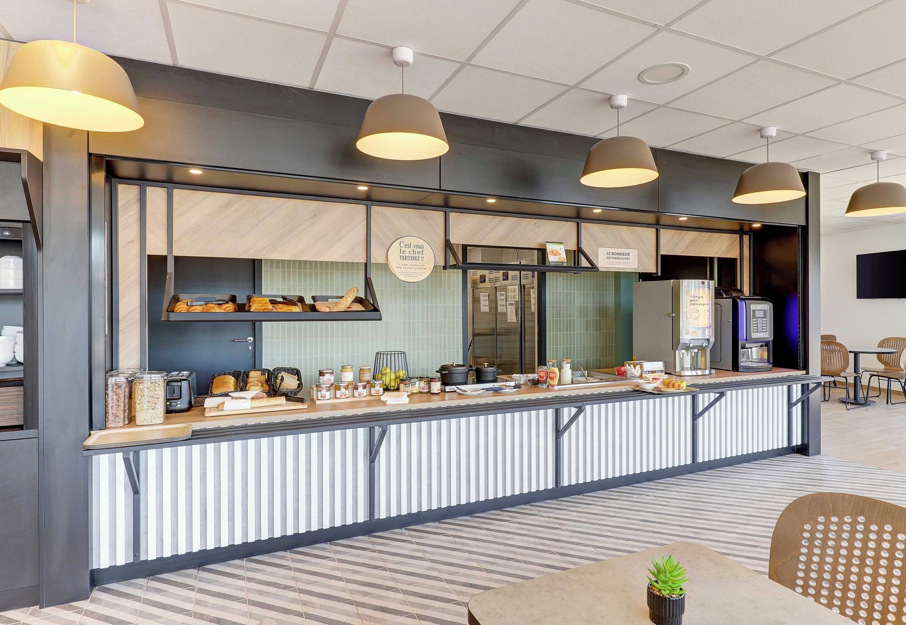 A modern counter with a variety of food items and a coffee machine, surrounded by seating areas.