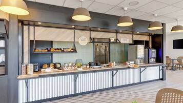 A modern counter with a variety of food items and a coffee machine, surrounded by seating areas.